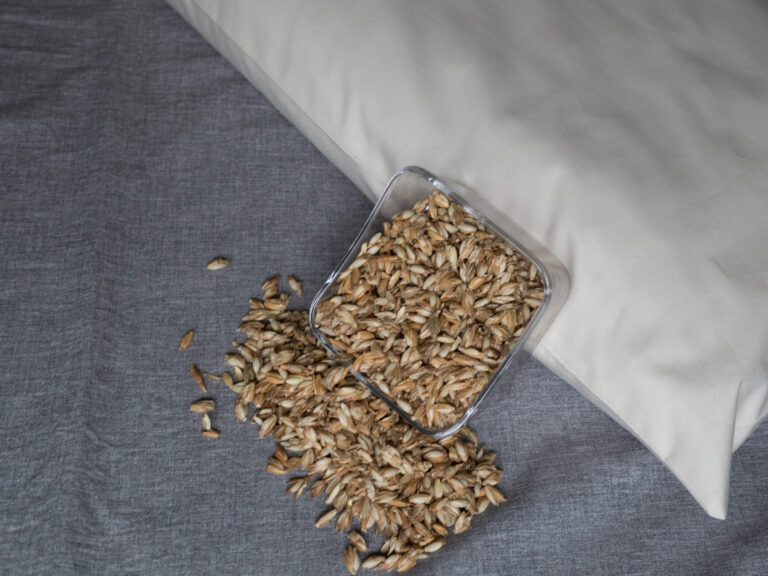 Dinkelspelzen in Glasschüssel an ein Körnerkopfkissen angelehnt. Dinkelfüllung für Körnerkopfkissen.